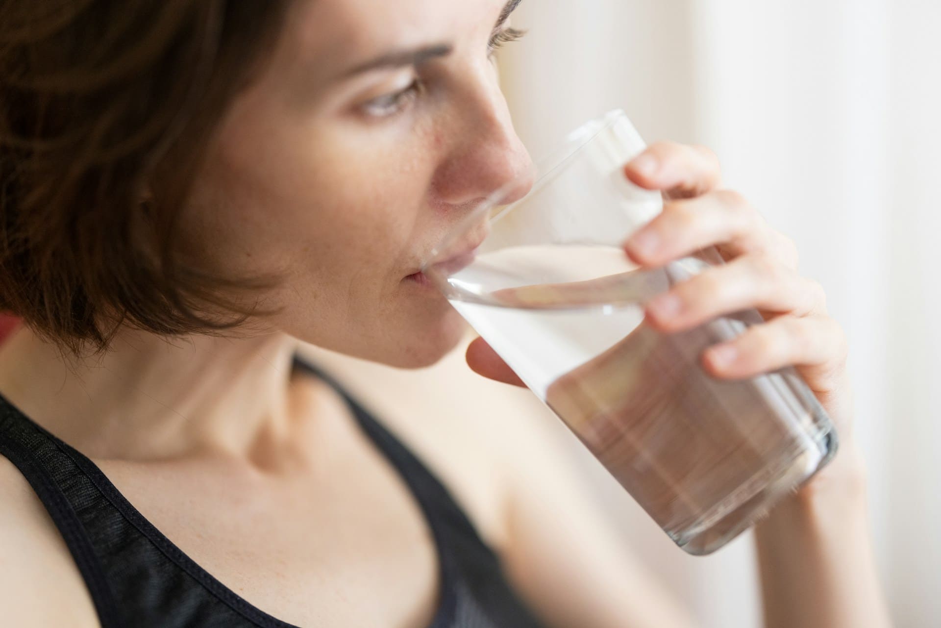 Foto de uma mulher bebendo água para manter a hidratação do corpo.